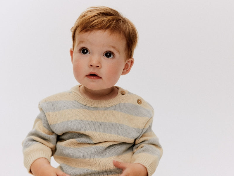 ein Baby mit einem blau gestreiften Pullover
