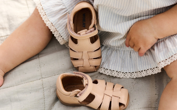 ein Baby mit einem Paar rosa Sandalen